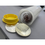 Open silver coin storage tube with its yellow lid removed, Maple Leaf coins stacked beside it